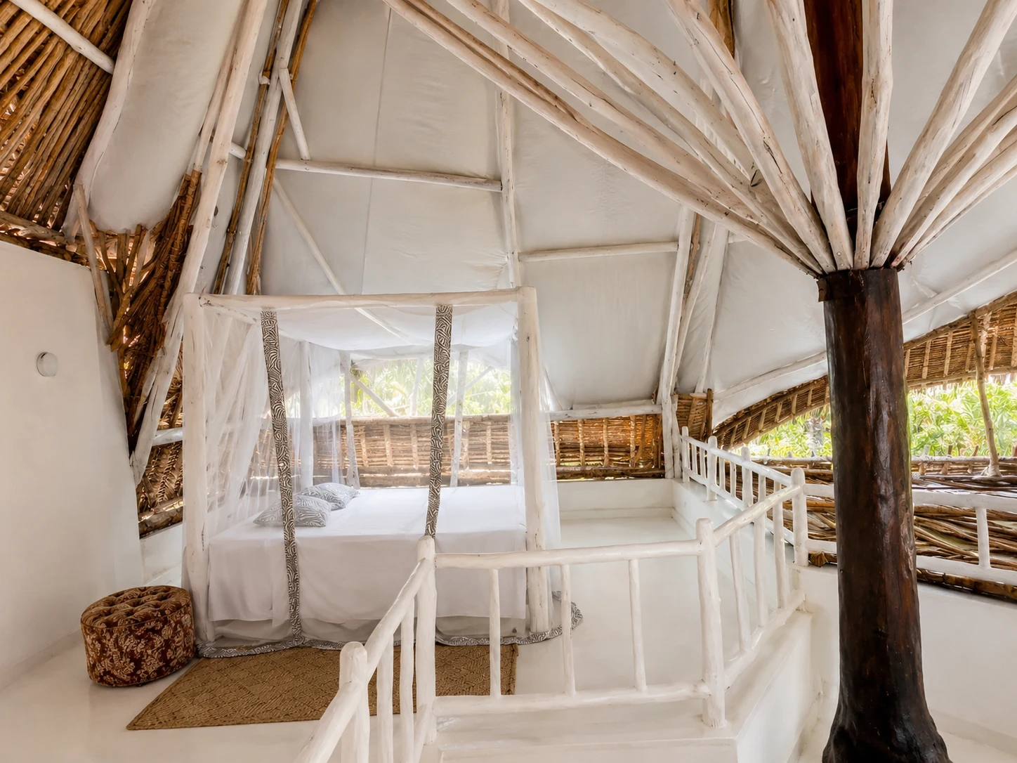 Loft bedroom at Cali Blossom Villa seen from the whitewashed staircase, with garden views through the open wall