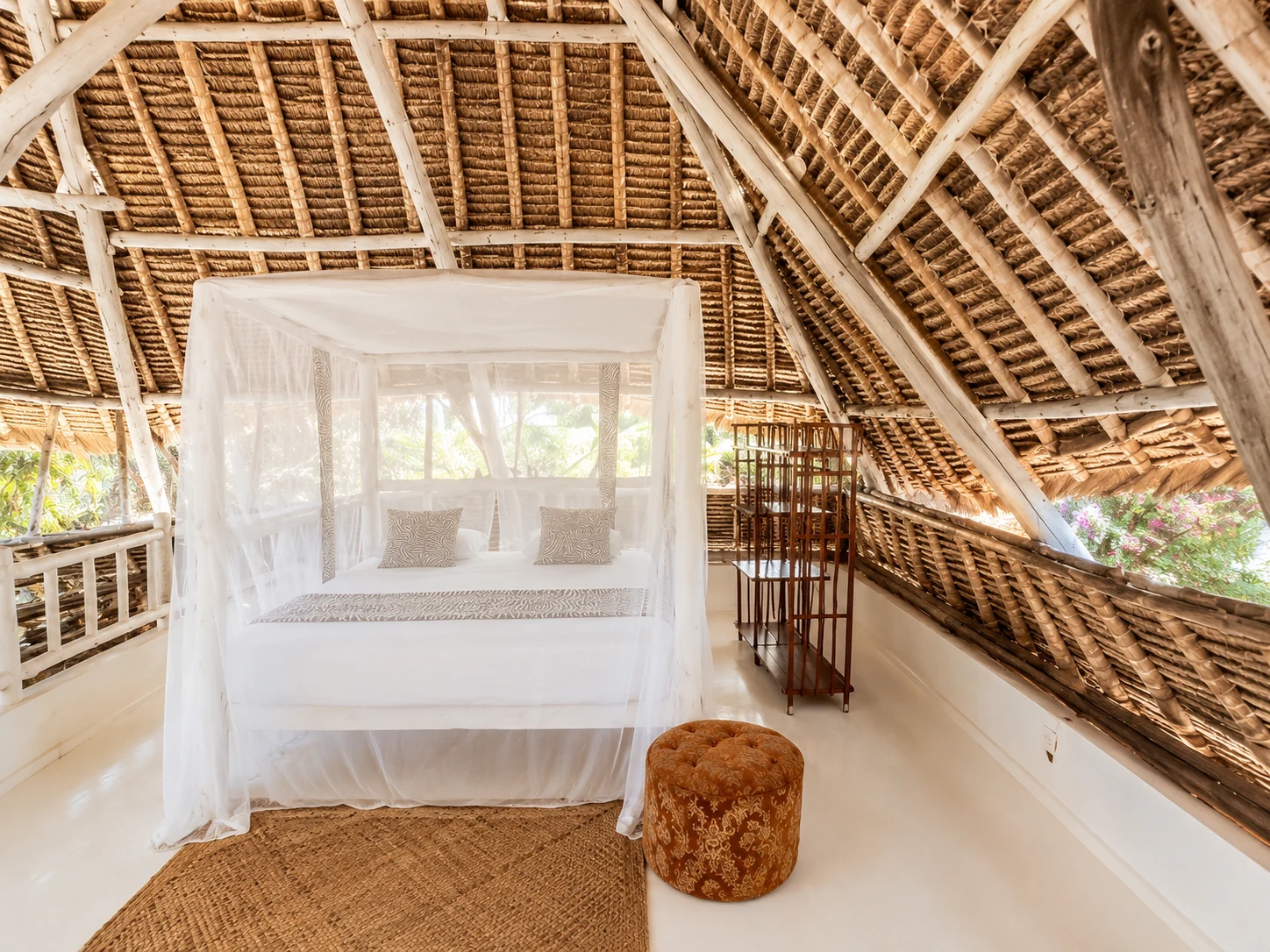 Open loft bedroom at Cali Blossom Villa with a four-poster bed, mosquito net and woven makuti roof
