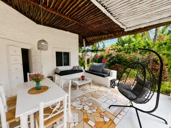 Terrace lounge at Cali Blossom Villa with cushioned seating and a hanging chair under the makuti roof