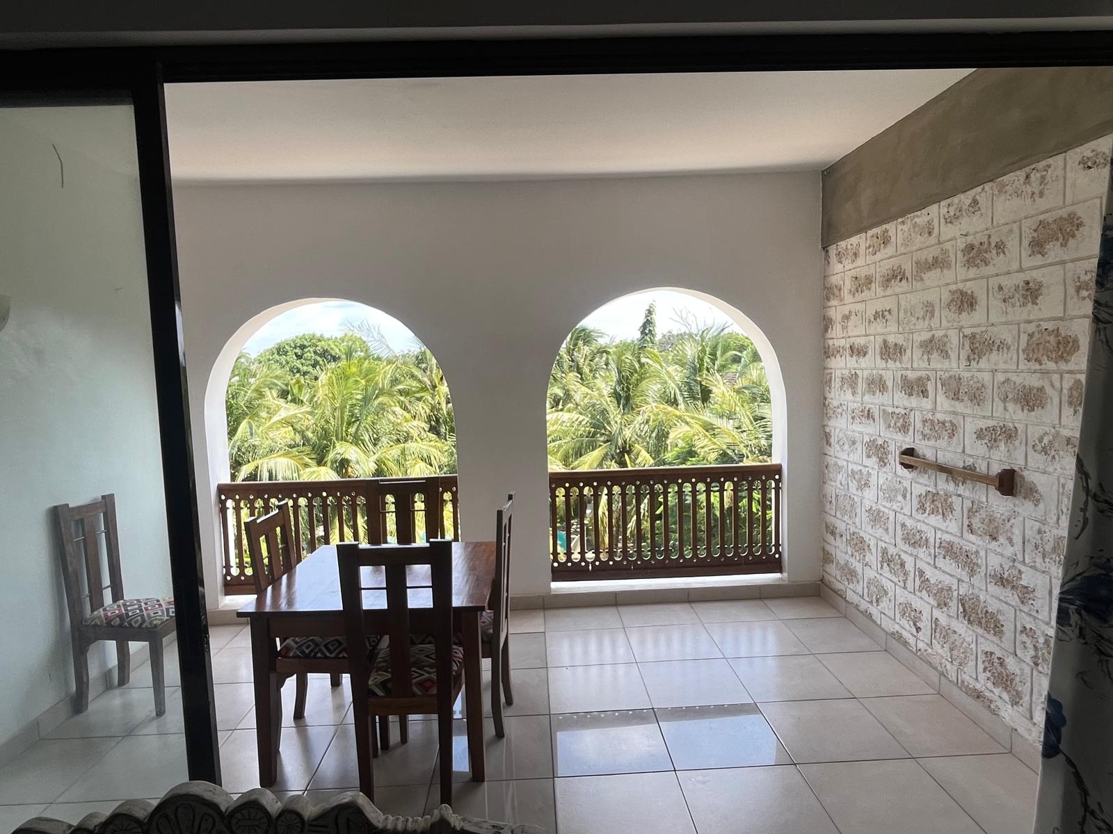 An arched Diani Stays balcony with dining table overlooking the palms